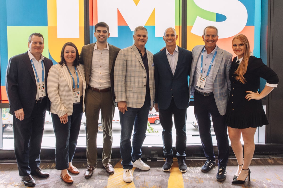Team of wealth advisors standing and smiling at an industry conference