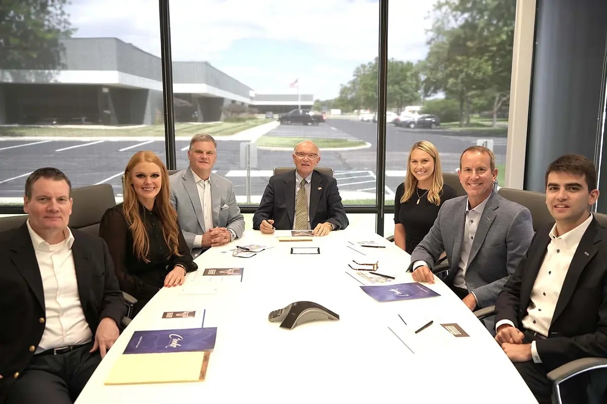 Wealth management team seated in a boardroom smiling at the camera